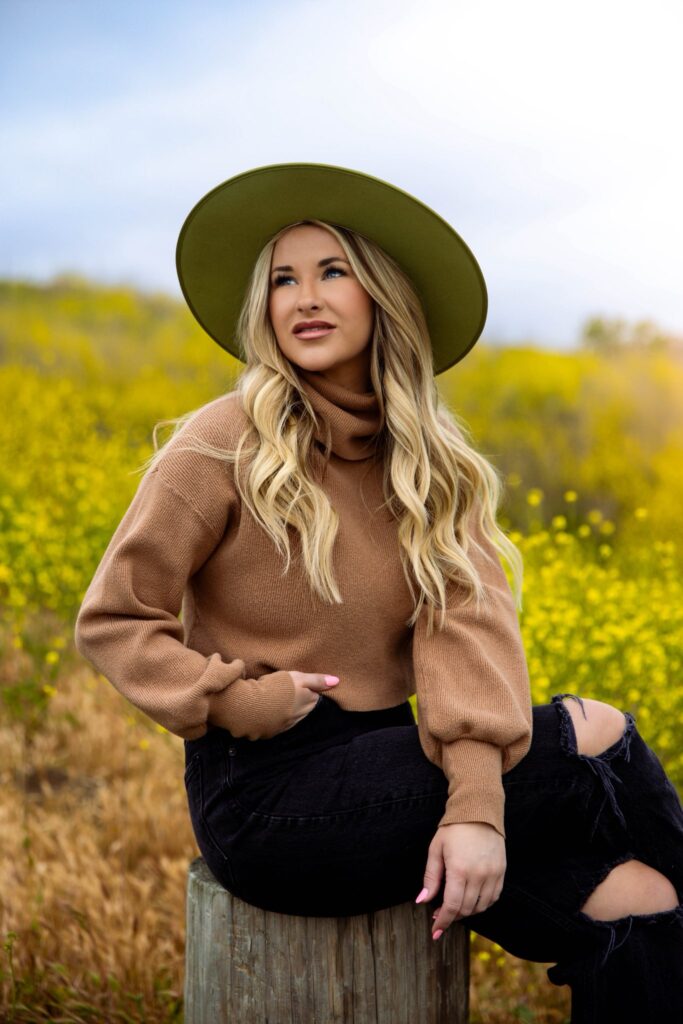 woman sitting on log in field
