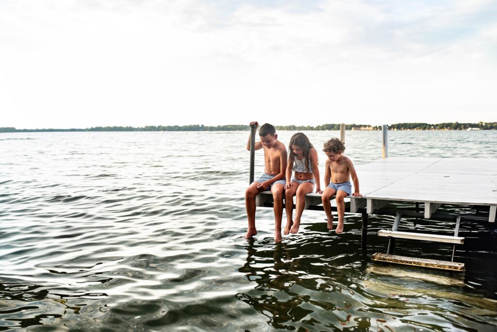 three siblings at the lake sitting on dock