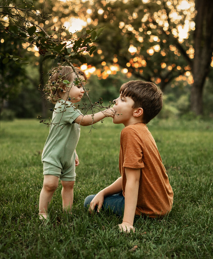 older and younger sibling playing in nature