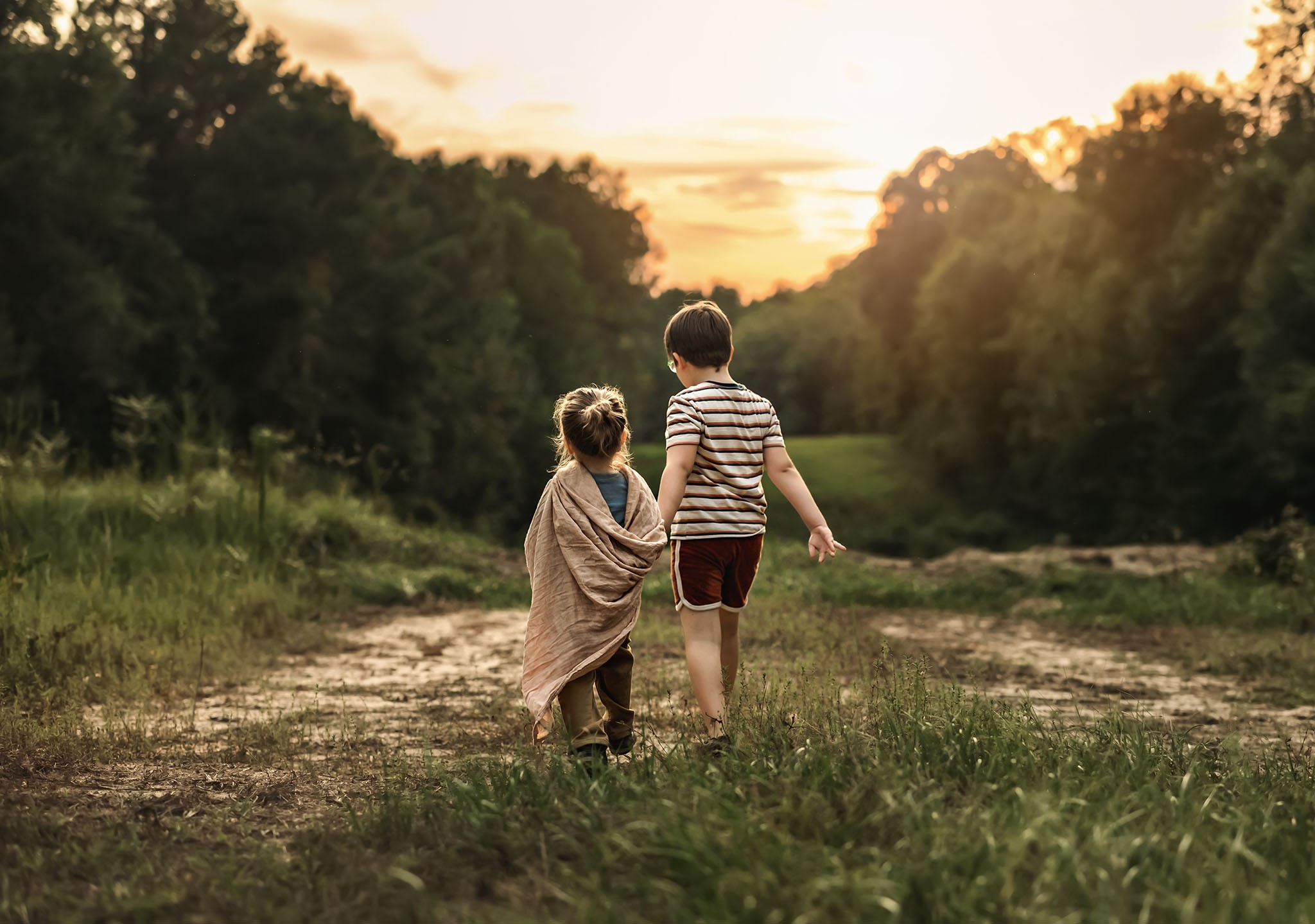 siblings holding hands walking in sunset