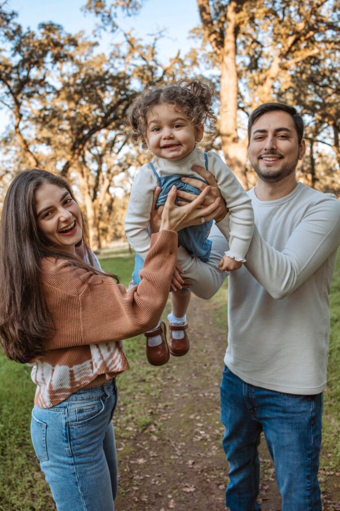 family of three portrait, all smiling at camera