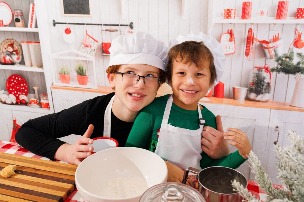 two young siblings smiling and baking in kitchen making a mess
