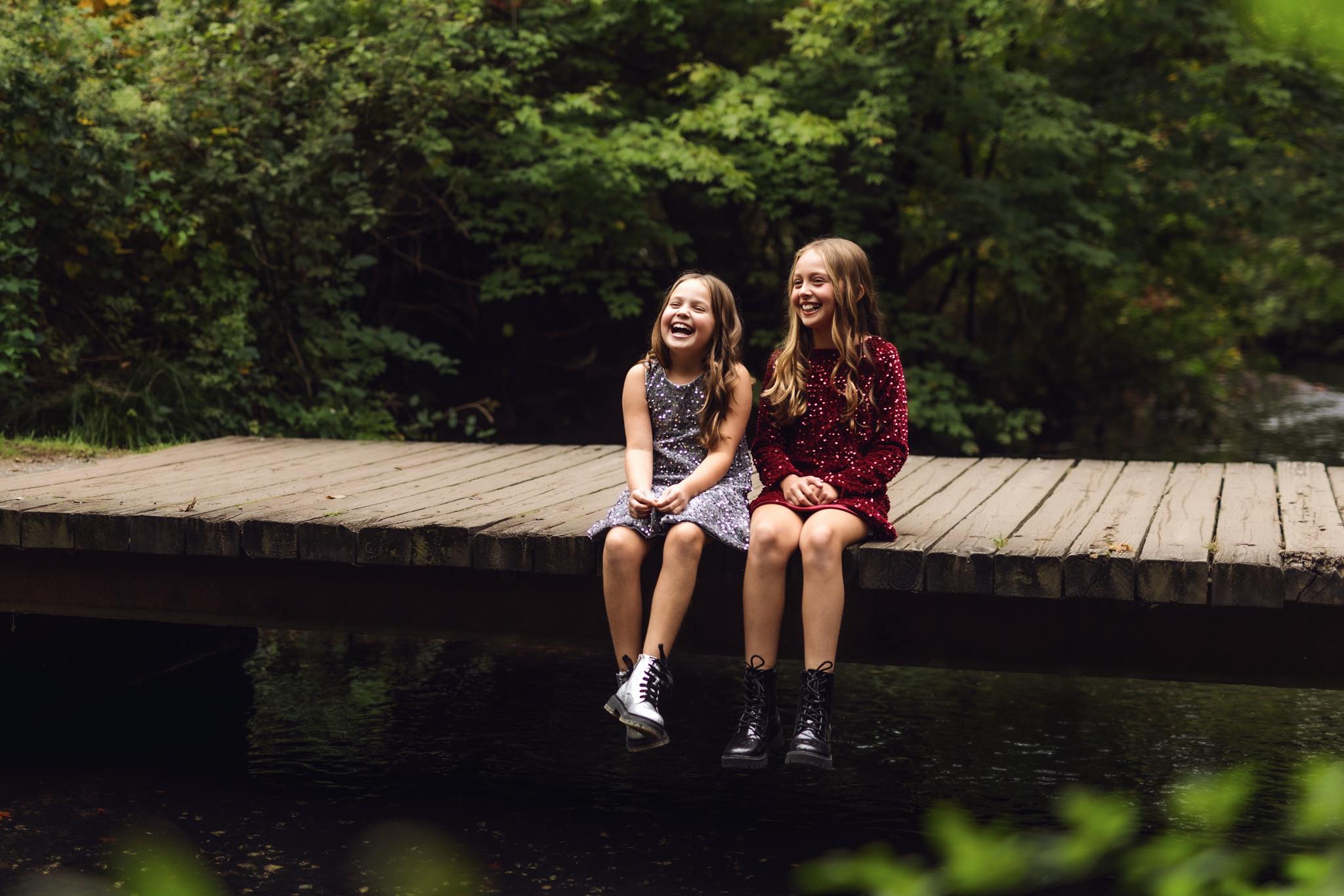 two young siblings sitting outside on a dock laughing together
