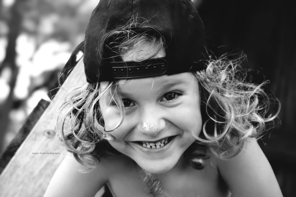 portrait of a smiling child wearing a hat backwards