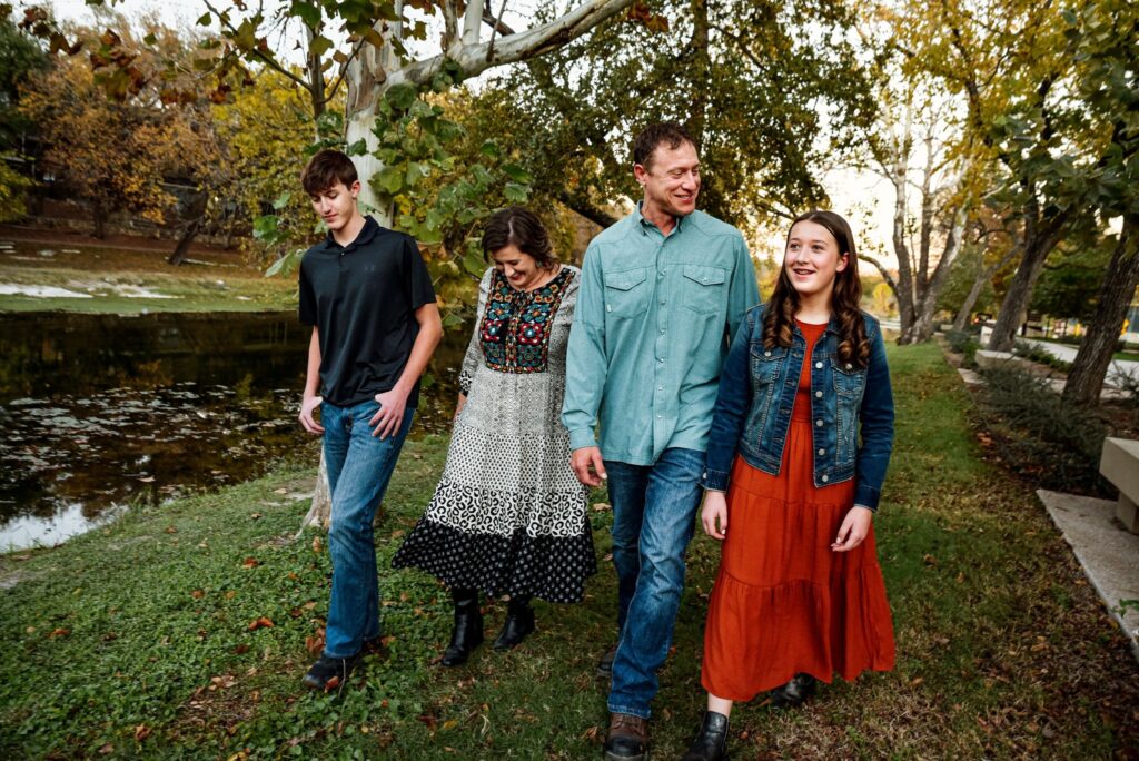 candid of family of four walking together at park