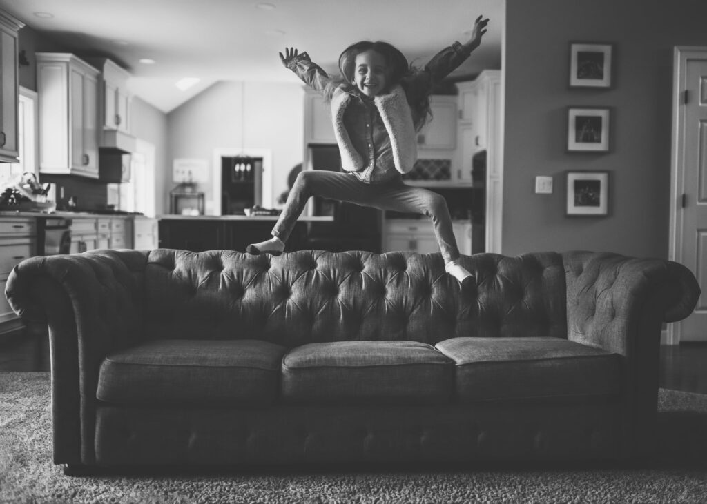 Child jumping on the couch captured in black and white