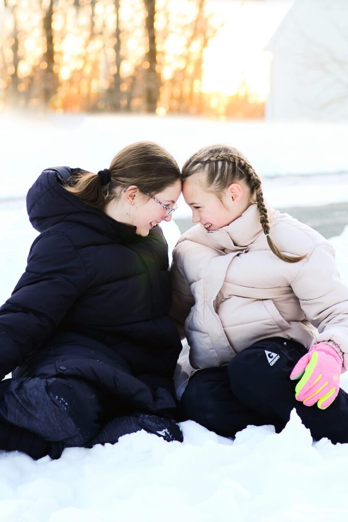 Friends laughing while sitting in snow