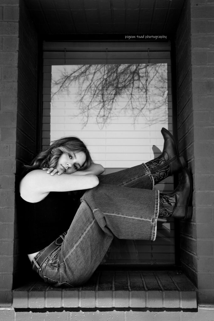 portrait of a girl sitting in between a building structure - black and white