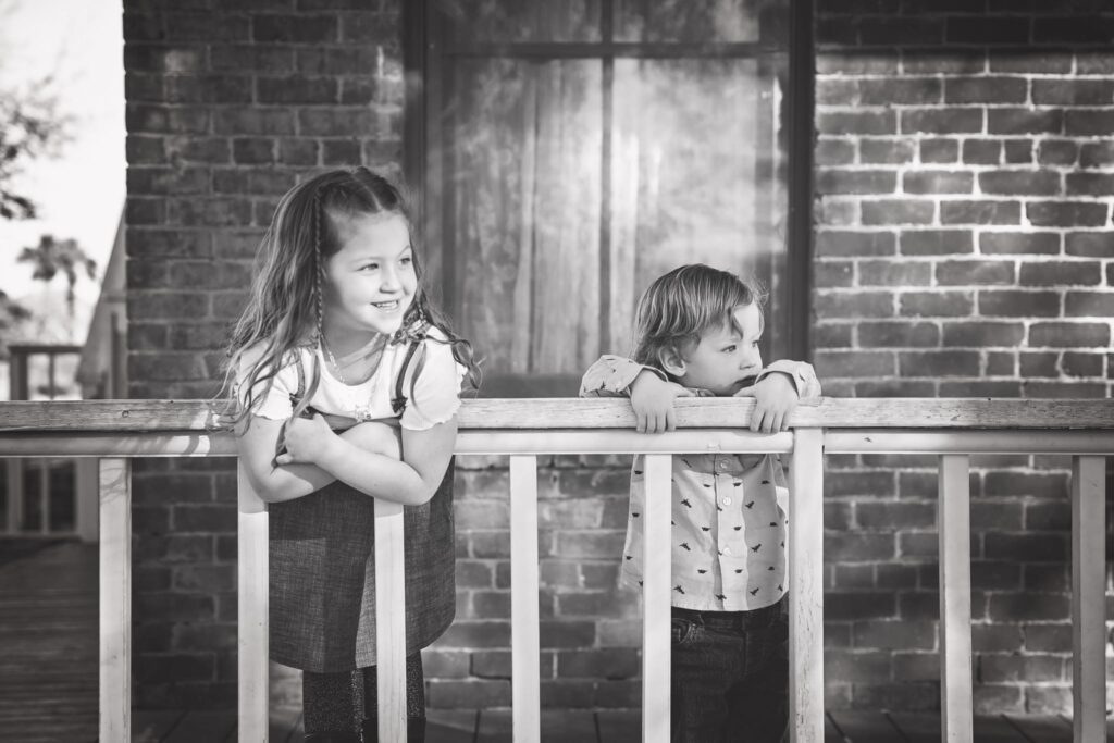 black and white portrait siblings smiling and looking to the right of camera