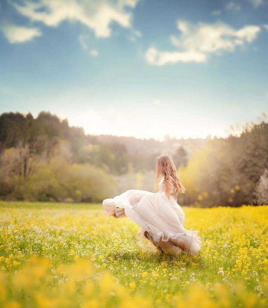 girl running in field of yellow flowers under blue sky