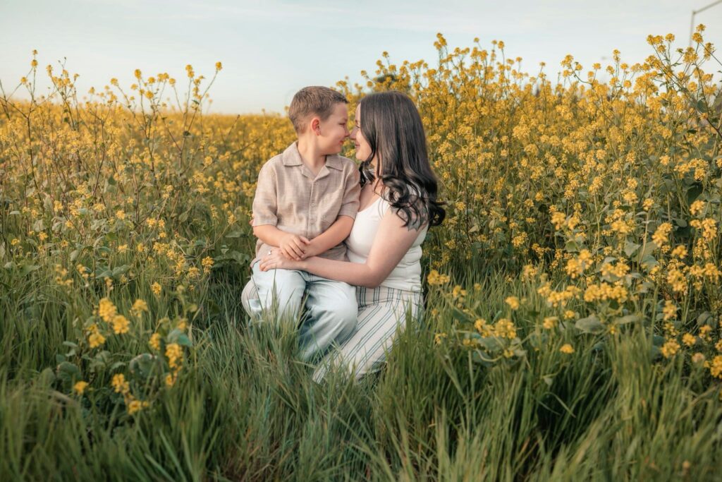 mother and son looking at each other sitting in a field of flowers