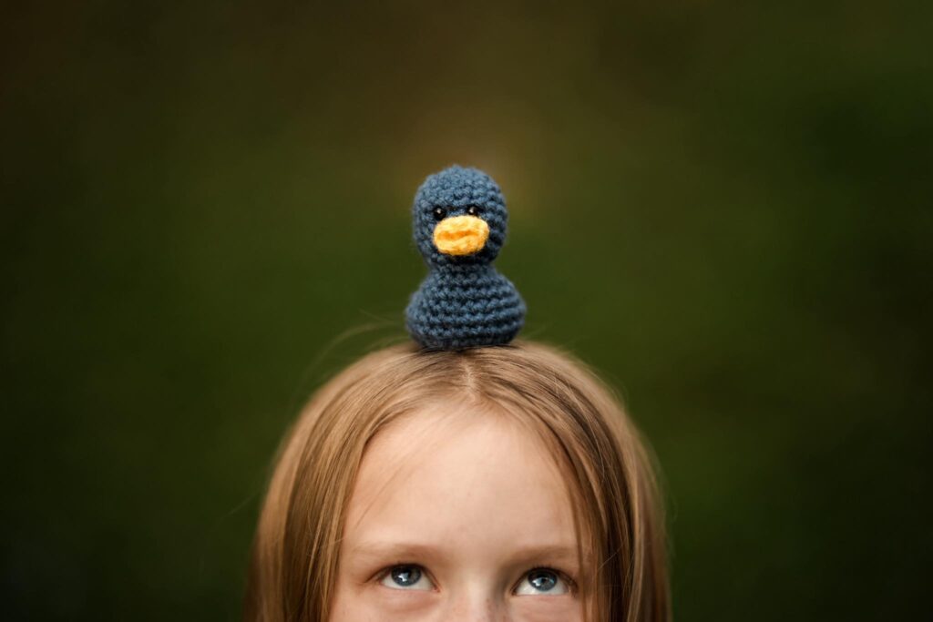 Spring theme - doll duck sitting on top of child's head, view of kid looking up at duck (cropped at the eyes)