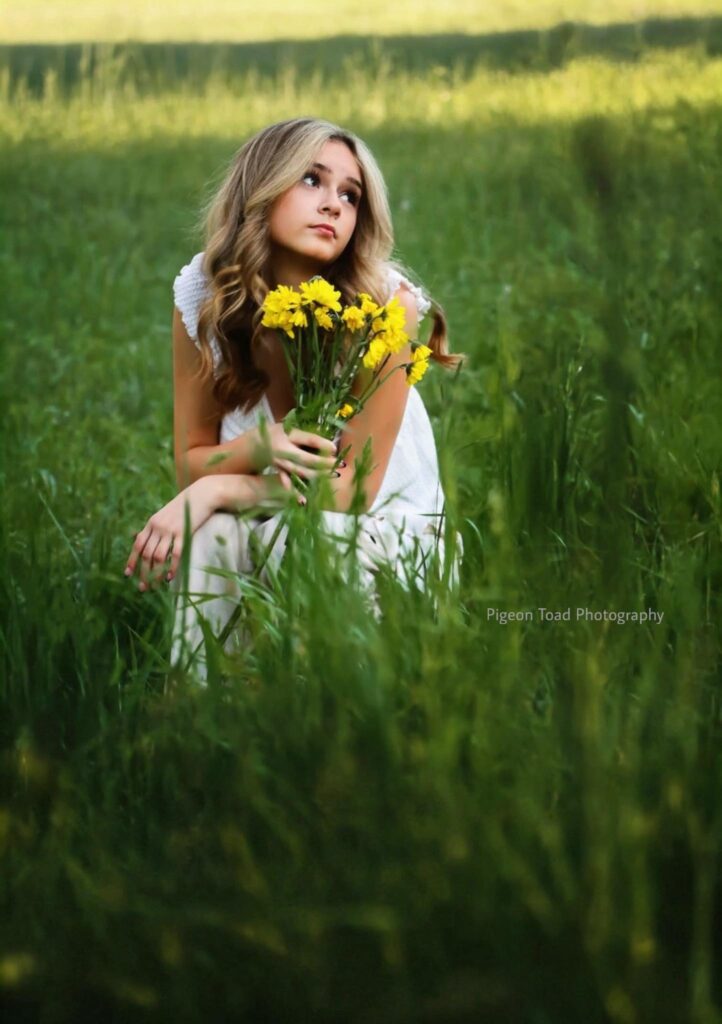 spring portrait of girl sitting in grass holding flowers