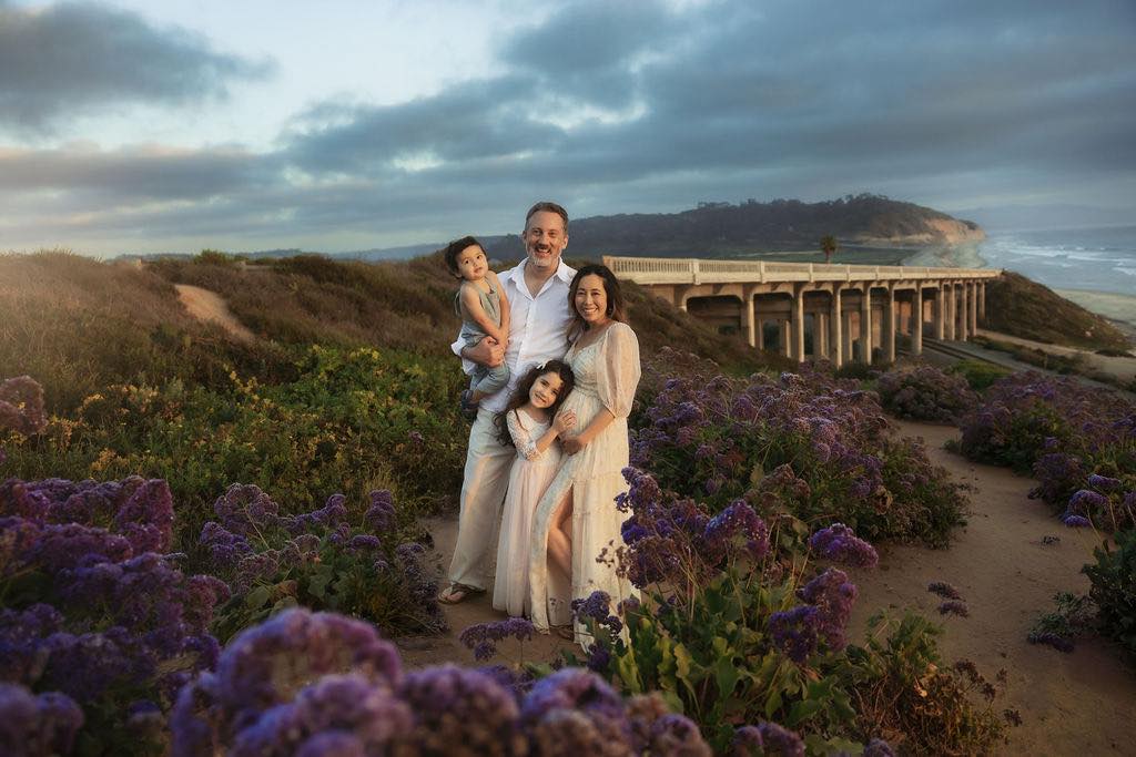 family portrait in a field of purple flowers with a bridge in background