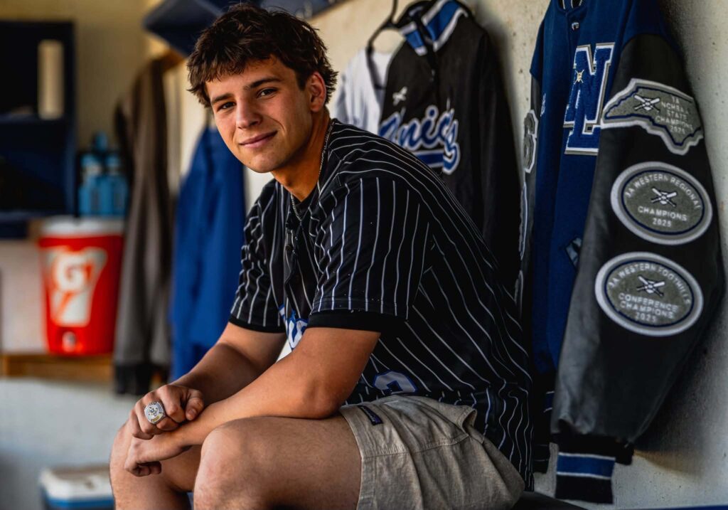 high school senior portrait of boy sitting in baseball dugout