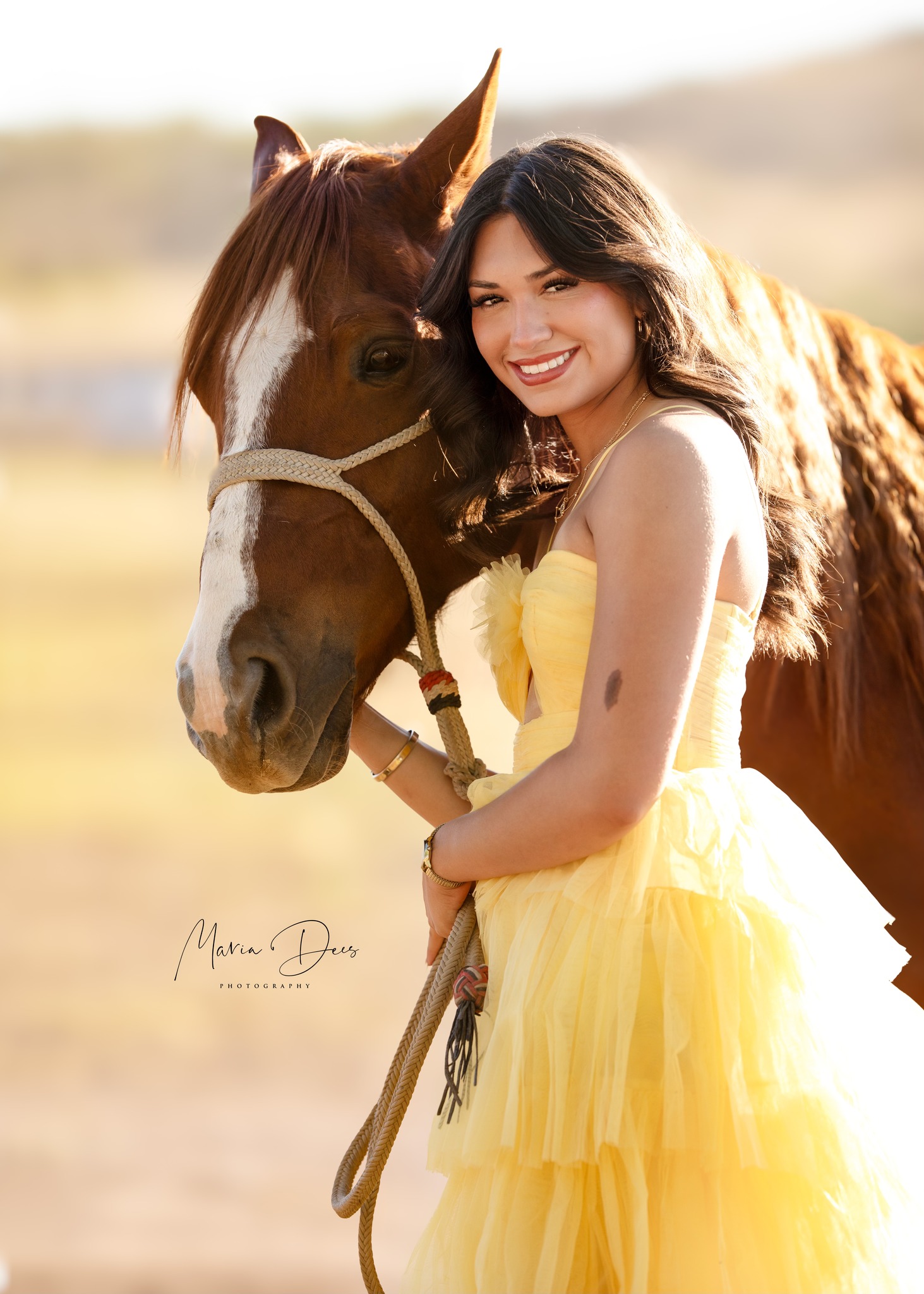 portrait of young woman in yellow dress smiling with a horse by her side